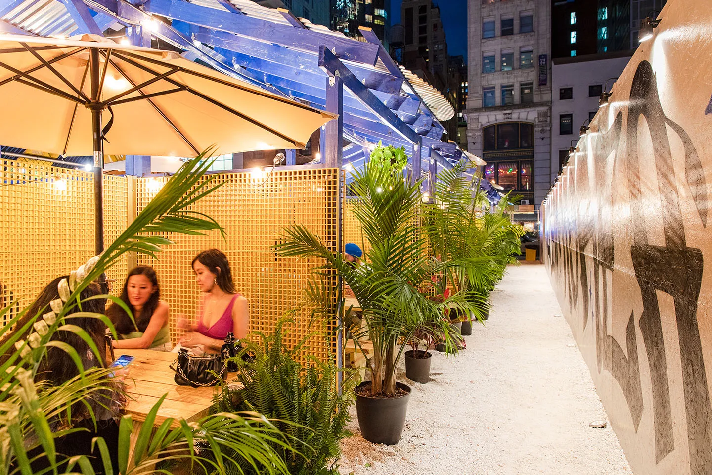 Guests at a table among palms under a market umbrella