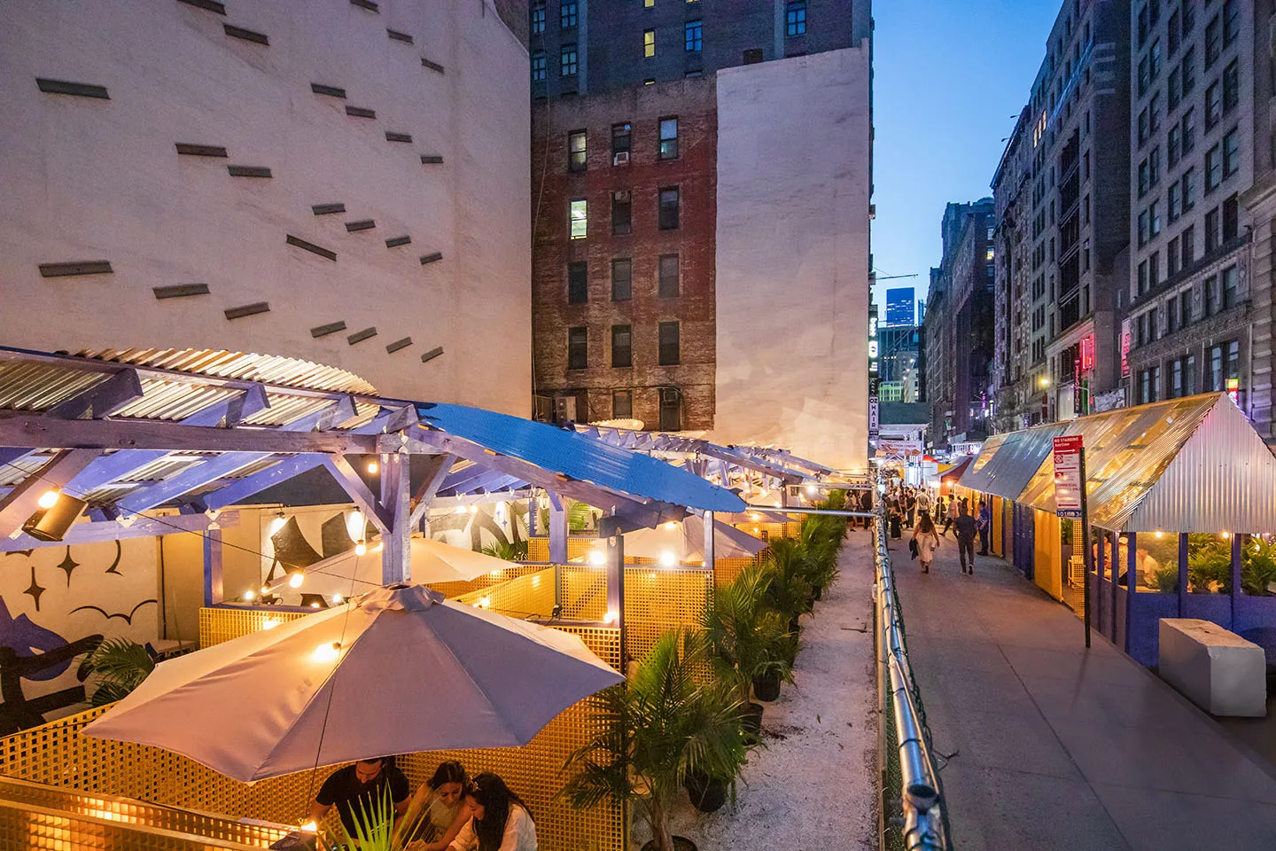 Blue canopies and umbrellas along the lot at night, Midtown towers behind