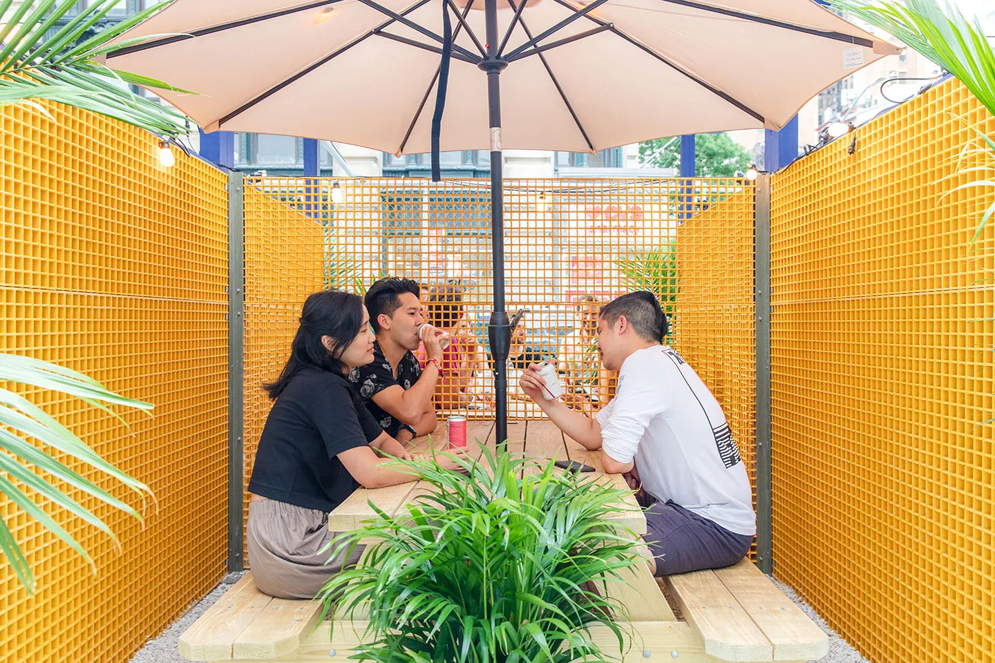 Two guests in a yellow mesh booth under an umbrella