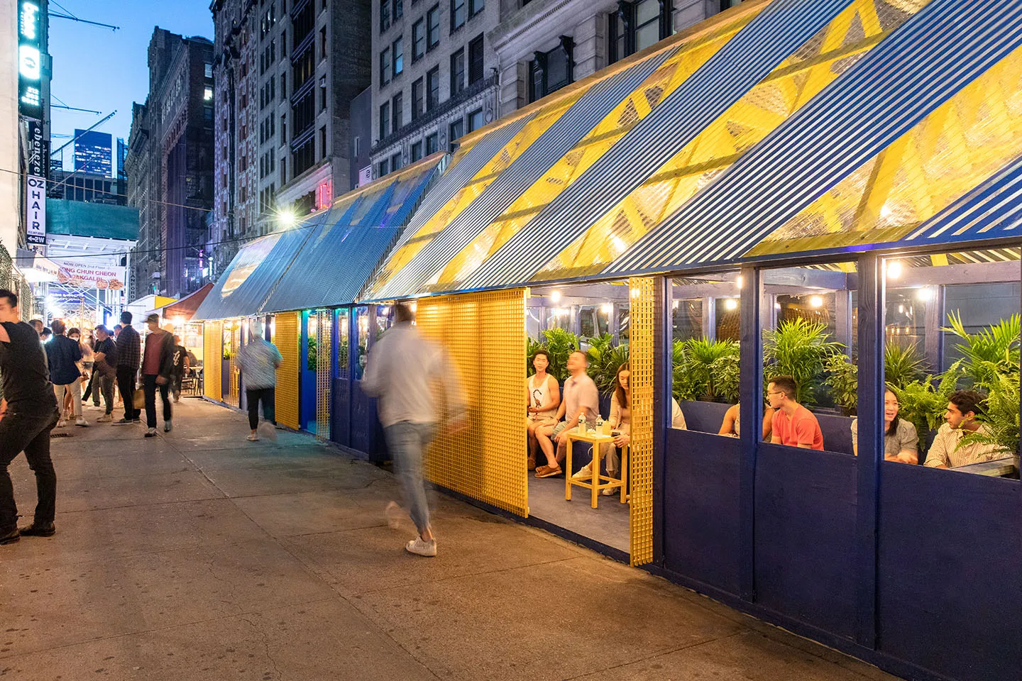 Cobalt and yellow pavilions glowing along the sidewalk at night